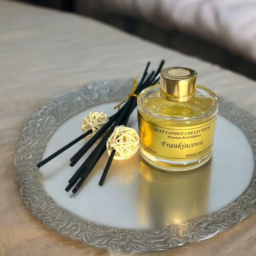 Frankincense Reed Diffuser Bottle with reeds on the side on a table in a tray
